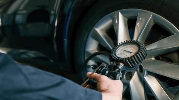 Technician checking tire pressure with a digital gauge in a service bay